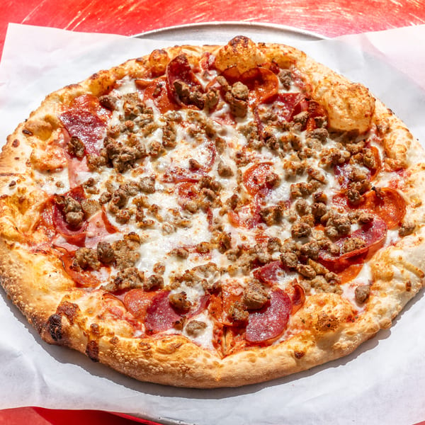 Golden-crusted pizza topped with pepperoni and crumbled sausage on a metal tray.
